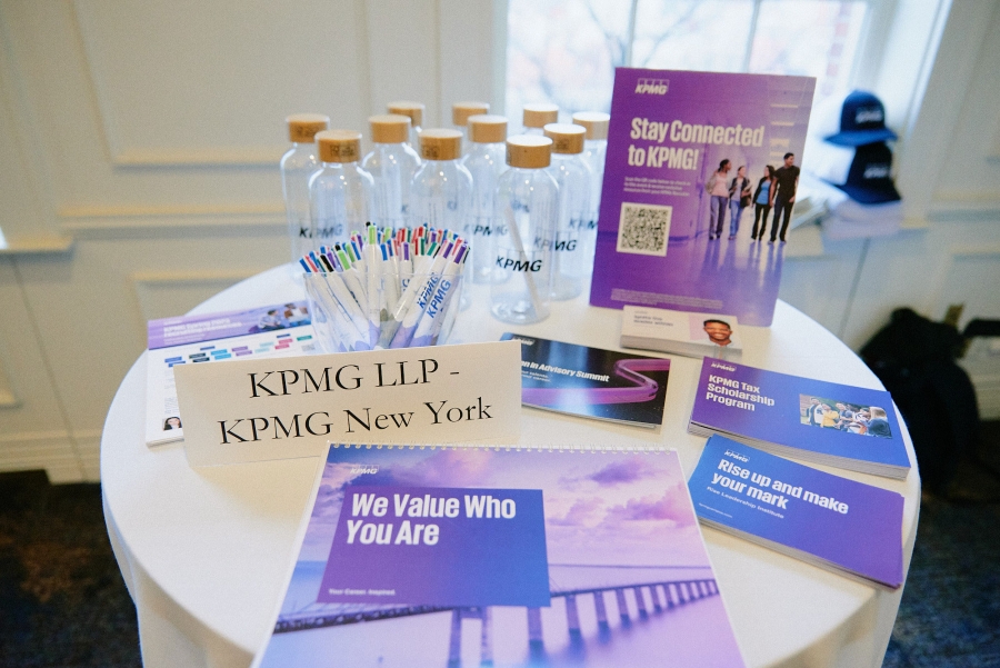 KPMG employer table display with flyers, water bottles and table sign that says "KPMG LLP" at the 2023 Diversity Recruiting Showcase